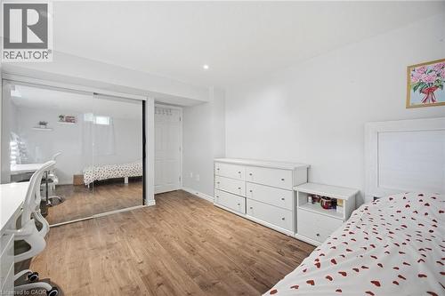 Bedroom featuring wood-finish flooring, a mirrored sliding closet door, recessed lighting, and a white paneled door - 58 Doon Creek Street, Kitchener, ON - Indoor Photo Showing Bedroom