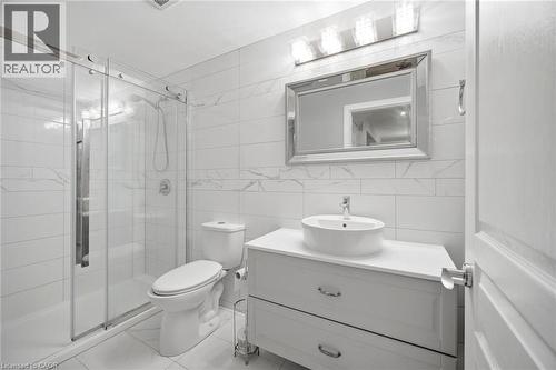 Full bathroom featuring a glass-enclosed shower, white subway-style wall tiling with a decorative accent band, and a vanity with a vessel sink and chrome hardware - 58 Doon Creek Street, Kitchener, ON - Indoor Photo Showing Bathroom