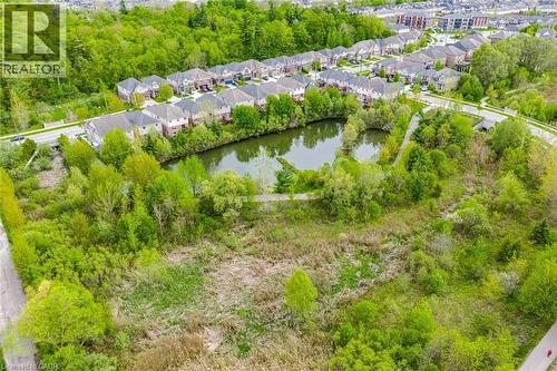 Aerial perspective showcasing a residential area with a prominent natural pond surrounded by lush green foliage - 58 Doon Creek Street, Kitchener, ON - Outdoor With View