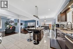Spacious kitchen featuring white tile flooring, a large island with a stone countertop, dark wood-finish cabinetry, and a subway tile backsplash - 