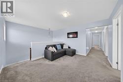 Upper-level landing featuring light blue wall paint, white trim, and gray carpet flooring - 