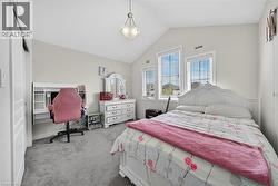 Carpeted bedroom featuring a vaulted ceiling with a semi-flush mount light fixture, multiple windows with blinds, and a built-in desk unit - 