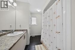 Bathroom featuring a single vanity with an integrated sink, a speckled countertop, and a large wall-mounted mirror - 