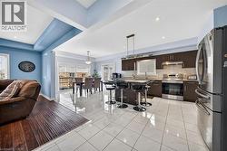 Open-concept living space featuring a modern kitchen with dark wood-finish cabinetry, stainless steel appliances, and a central island with seating - 