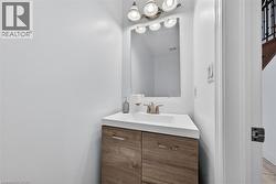 Powder room featuring a wood-finish vanity with a white countertop and integrated sink - 