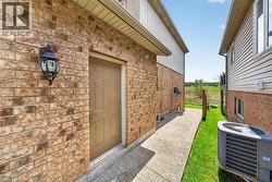 Brick exterior with a side entry door, exterior wall lantern, and concrete pathway - 