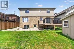 Rear exterior featuring a brick and siding facade, elevated wood deck with black railings, ground-level concrete patio, sliding glass door access, and a detached storage shed - 