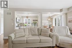Open-concept living area featuring light neutral walls, wood-finish flooring, and recessed lighting - 