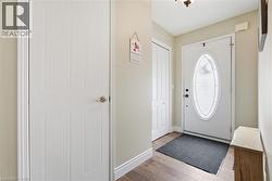 Entryway featuring an oval glass-paneled door, wood-finish flooring, two additional panel doors, and neutral wall paint - 