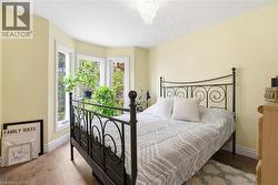 Bedroom featuring a bay window, wood-finish flooring, a chandelier fixture, and a textured ceiling - 