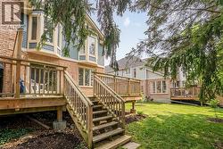 Rear exterior featuring a multi-level wood deck with stairs to the lawn - 