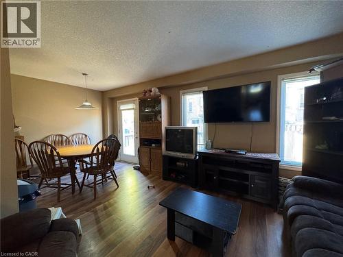 Open-concept living area featuring wood-finish flooring, ample natural light from multiple windows, and a glass-paneled exterior door - 517 Northbrook Place, Kitchener, ON - Indoor Photo Showing Living Room