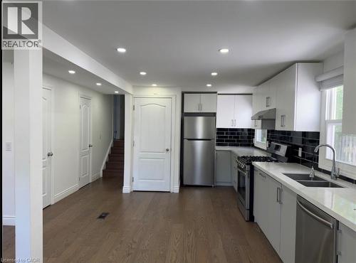 Contemporary kitchen featuring stainless steel appliances, white cabinetry, black subway tile backsplash, and light-toned countertops - 28 Timberlane Crescent Unit# Upper, Kitchener, ON - Indoor Photo Showing Kitchen With Double Sink