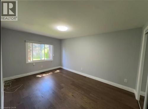 Spacious room featuring wood-finish flooring, light gray walls, a large window, a ceiling-mounted light fixture, and white baseboards - 28 Timberlane Crescent Unit# Upper, Kitchener, ON - Indoor Photo Showing Other Room
