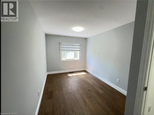 Spacious room featuring wood-finish flooring, light gray wall finishes, a window with horizontal blinds, and a flush-mount ceiling light - 28 Timberlane Crescent Unit# Upper, Kitchener, ON - Indoor Photo Showing Other Room