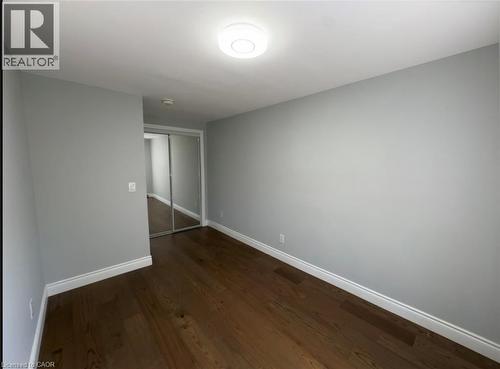 Room featuring wood-finish flooring, light gray wall paint, white baseboards, and a mirrored closet door - 28 Timberlane Crescent Unit# Upper, Kitchener, ON - Indoor Photo Showing Other Room