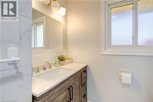 Bathroom vanity with a light wood-finish cabinet, white countertop, and integrated sink - 100 Lauris Avenue, Cambridge, ON - Indoor Photo Showing Bathroom
