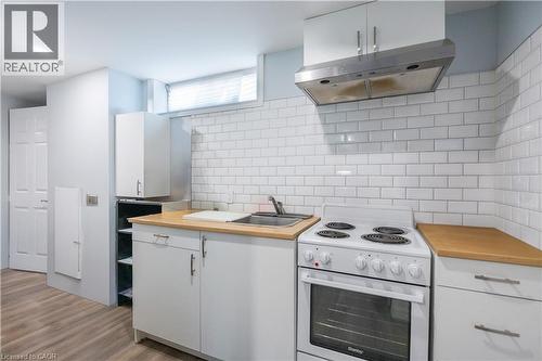 Kitchenette featuring white cabinetry, wood-finish countertops, stainless steel sink, and subway tile backsplash - 100 Lauris Avenue, Cambridge, ON - Indoor Photo Showing Kitchen
