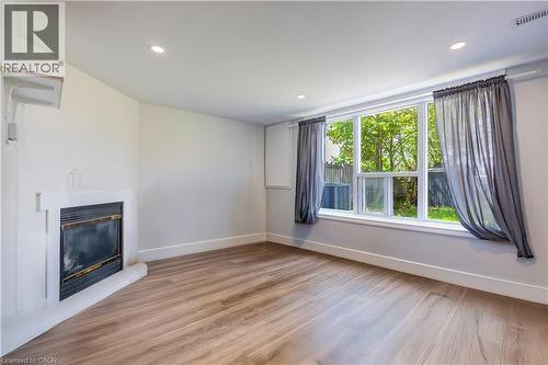 Spacious room featuring wood-finish flooring, a contemporary fireplace, and recessed lighting - 100 Lauris Avenue, Cambridge, ON - Indoor With Fireplace