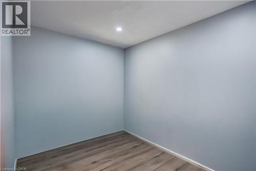 Room featuring light blue walls, recessed ceiling lighting, wood-finish flooring, and white baseboards - 100 Lauris Avenue, Cambridge, ON - Indoor Photo Showing Other Room