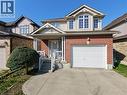 Brick and siding exterior featuring a covered front porch with white railing, an attached single-car garage, concrete driveway, and dormer windows - 28 Lemon Grass Street, Kitchener, ON  - Outdoor 