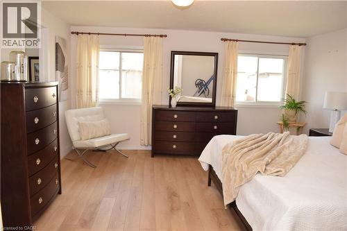 Light wood-finish flooring provides a bright foundation in this room featuring two windows with white trim - 28 Lemon Grass Street, Kitchener, ON - Indoor Photo Showing Bedroom