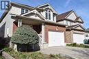 Brick and siding exterior featuring a covered porch with white railings, a front-facing dormer with multiple windows, and an attached two-car garage with a paved driveway - 28 Lemon Grass Street, Kitchener, ON  - Outdoor 