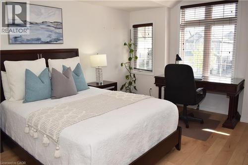 Bedroom featuring light wood-finish flooring, white walls, and a dark wood bed frame - 28 Lemon Grass Street, Kitchener, ON - Indoor Photo Showing Bedroom