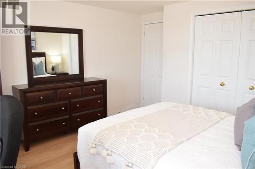Bedroom featuring light wood-finish flooring, white walls, and white bi-fold closet doors with brass-tone hardware - 28 Lemon Grass Street, Kitchener, ON - Indoor Photo Showing Bedroom