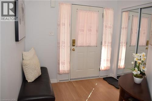 Entryway featuring wood-finish flooring, a white paneled door with side window, and sliding mirrored closet doors - 28 Lemon Grass Street, Kitchener, ON - Indoor