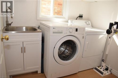 Dedicated laundry area featuring a front-load washer, companion dryer, and a stainless steel utility sink with a brushed nickel faucet - 28 Lemon Grass Street, Kitchener, ON - Indoor Photo Showing Laundry Room