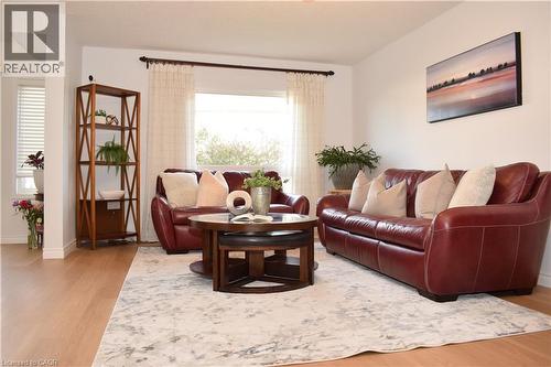 Bright living area featuring light wood-finish flooring, a large window with sheer drapes, and neutral wall tones - 28 Lemon Grass Street, Kitchener, ON - Indoor Photo Showing Living Room