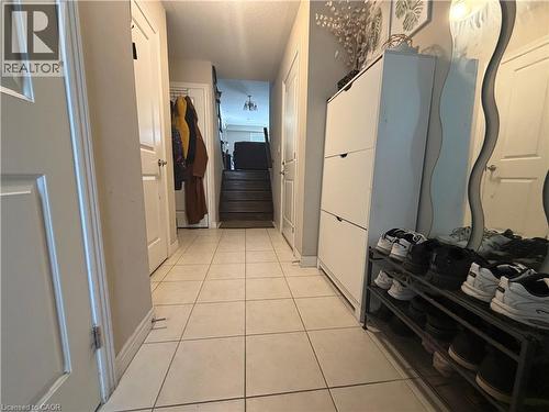 Tiled entryway with light-toned flooring extending to a staircase featuring dark wood treads - 25 Bethune Avenue, Hamilton, ON - Indoor Photo Showing Other Room