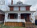Brick exterior featuring a covered porch with white railing, wood-finish porch skirt, and wood steps - 52 Emerson Street, Hamilton, ON  - Outdoor 