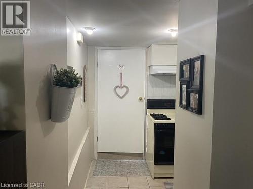 Compact kitchen area featuring a gas range, white cabinetry, and a range hood, complemented by tile flooring - 52 Emerson Street, Hamilton, ON - Indoor