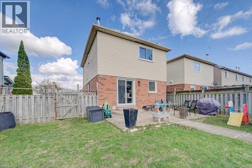 Rear exterior featuring a ground-level patio, sliding glass door, and brick and siding facade - 334 Christopher Drive, Cambridge, ON - Outdoor With Exterior