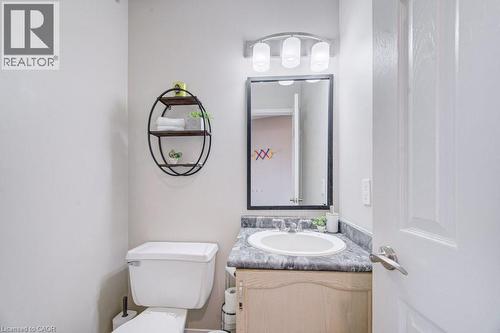 Bathroom vanity with a white oval basin, a speckled countertop, and a wood-finish cabinet - 334 Christopher Drive, Cambridge, ON - Indoor Photo Showing Bathroom