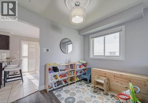 Spacious interior room featuring wood-finish flooring, a contemporary ceiling light fixture with decorative medallion, a large window with white trim, and light gray wall paint - 334 Christopher Drive, Cambridge, ON - Indoor