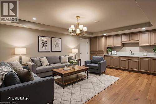 Spacious living area featuring wood-finish flooring, recessed lighting, and a brass chandelier - 643 Artreva Crescent, Burlington, ON - Indoor Photo Showing Living Room