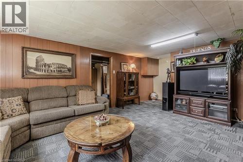 Wood-paneled wall accents a recreation room with patterned carpeting - 643 Artreva Crescent, Burlington, ON - Indoor Photo Showing Living Room