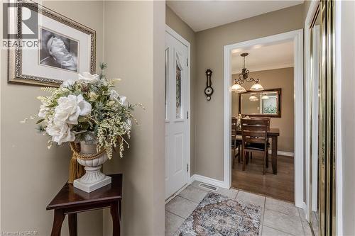 Warm entry foyer with tile flooring leading to a dining area featuring wood-finish flooring and a decorative chandelier - 643 Artreva Crescent, Burlington, ON - Indoor Photo Showing Other Room