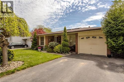 Brick facade home featuring a single-car garage with decorative windows, a paved driveway, and established landscaping - 643 Artreva Crescent, Burlington, ON - Outdoor