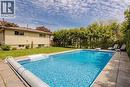 In-ground swimming pool with integrated steps, surrounded by stone paver decking and mature privacy landscaping - 643 Artreva Crescent, Burlington, ON  - Outdoor With In Ground Pool With Backyard 