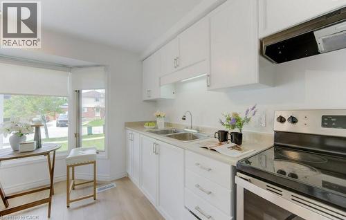 White cabinetry kitchen featuring a dual-basin stainless steel sink, light-toned countertops, and a stainless steel electric range with an overhead vent - 603 Pinerow Crescent Unit# B, Waterloo, ON 