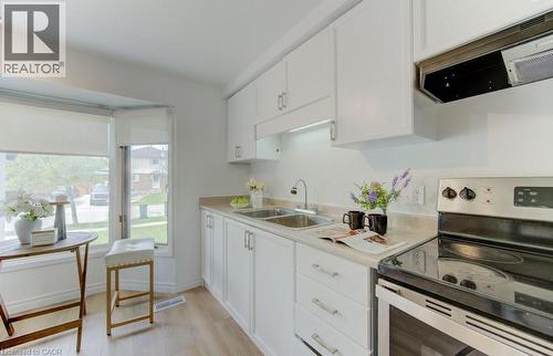 Bright kitchen featuring white cabinetry, light countertops, wood-finish flooring, a stainless steel electric range, and a bay window - 603 Pinerow Crescent Unit# B, Waterloo, ON 