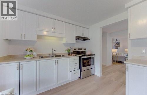 Bright kitchen featuring white cabinetry, a double basin stainless steel sink, stainless steel range, and light wood-finish flooring - 603 Pinerow Crescent Unit# B, Waterloo, ON 
