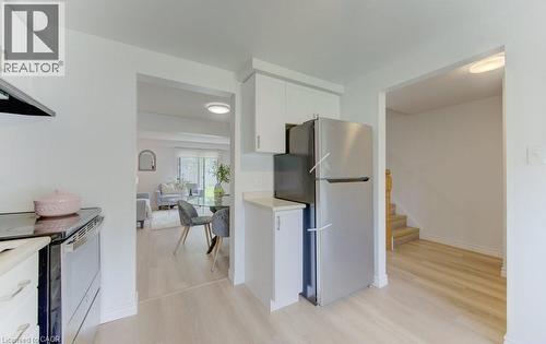 Bright kitchen area with white cabinetry, stainless steel refrigerator, and wood-finish flooring - 603 Pinerow Crescent Unit# B, Waterloo, ON 