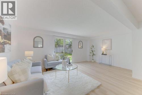 Spacious living area featuring light wood-finish flooring, white walls, and sliding glass doors leading to the exterior - 603 Pinerow Crescent Unit# B, Waterloo, ON 