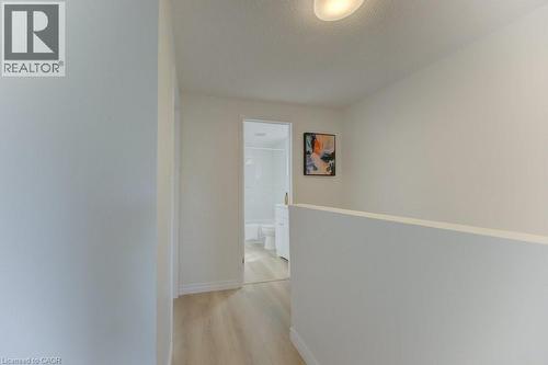 Hallway featuring wood-finish flooring, white walls, and a recessed ceiling light fixture - 603 Pinerow Crescent Unit# B, Waterloo, ON 
