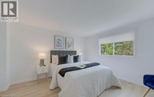 Bright bedroom featuring a large window, light wood-finish flooring, white walls, and white baseboards - 603 Pinerow Crescent Unit# B, Waterloo, ON 